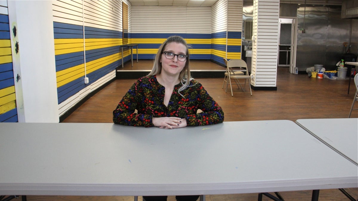 Laure Biron, director of the Porch Light Program for Philadelphia Mural Arts, sits in the program's newly burnished storefront on Kensington Avenue. (Emma Lee/WHYY)