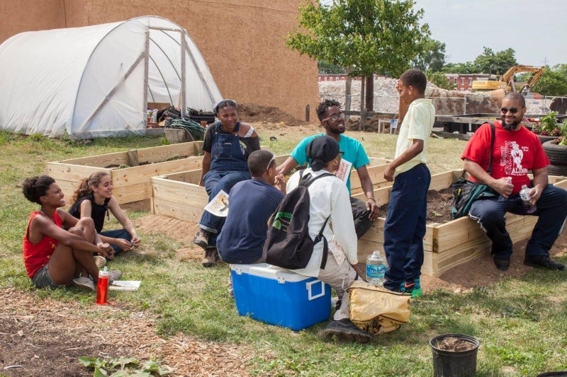 Maya Thomas (left) sits on a raised planter bed in North Philadelphia Peace Park