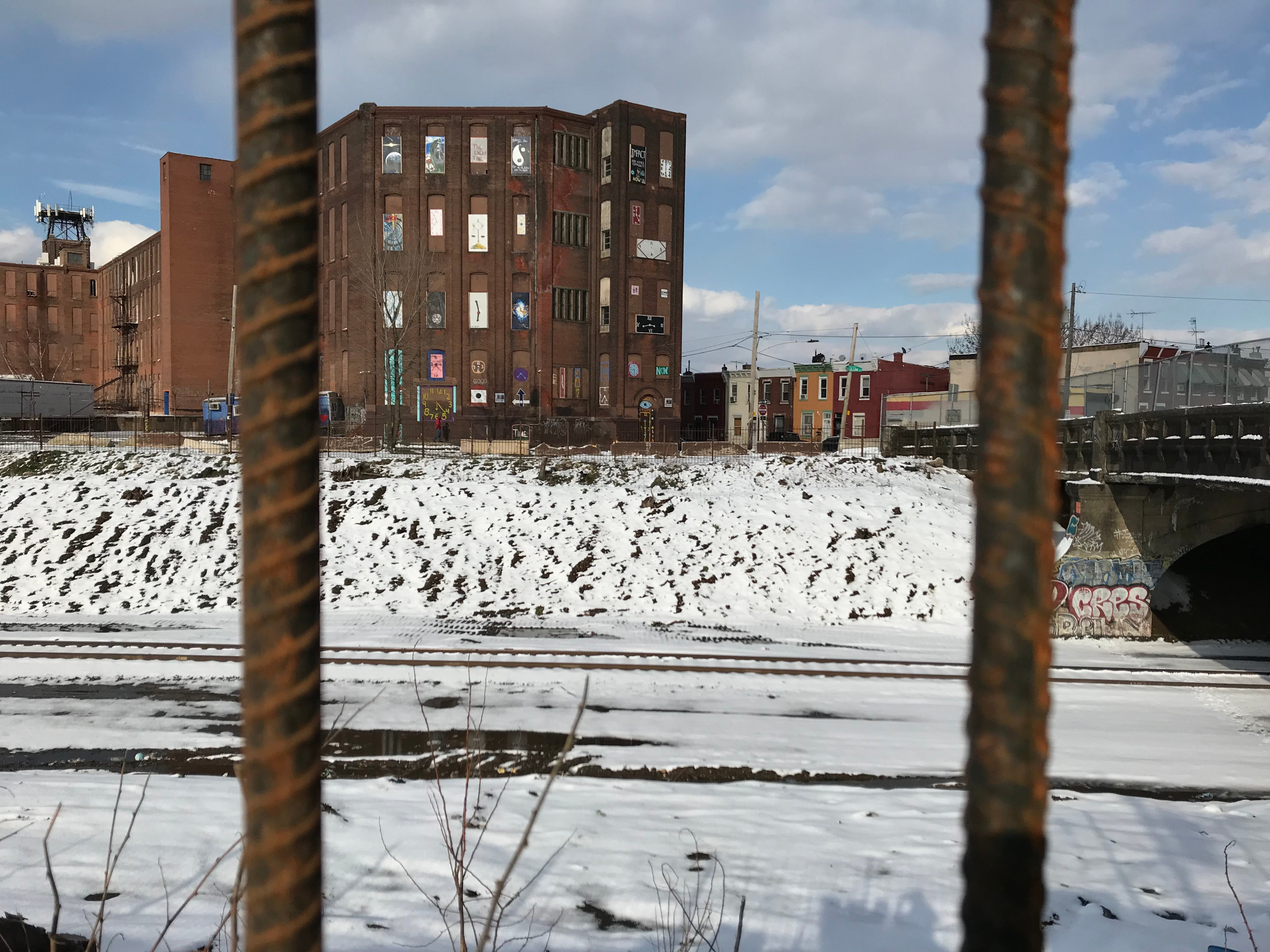 The textile mill, decorated with a new mural, overlooks the Conrail tracks. (Joel Wolfram for WHYY)