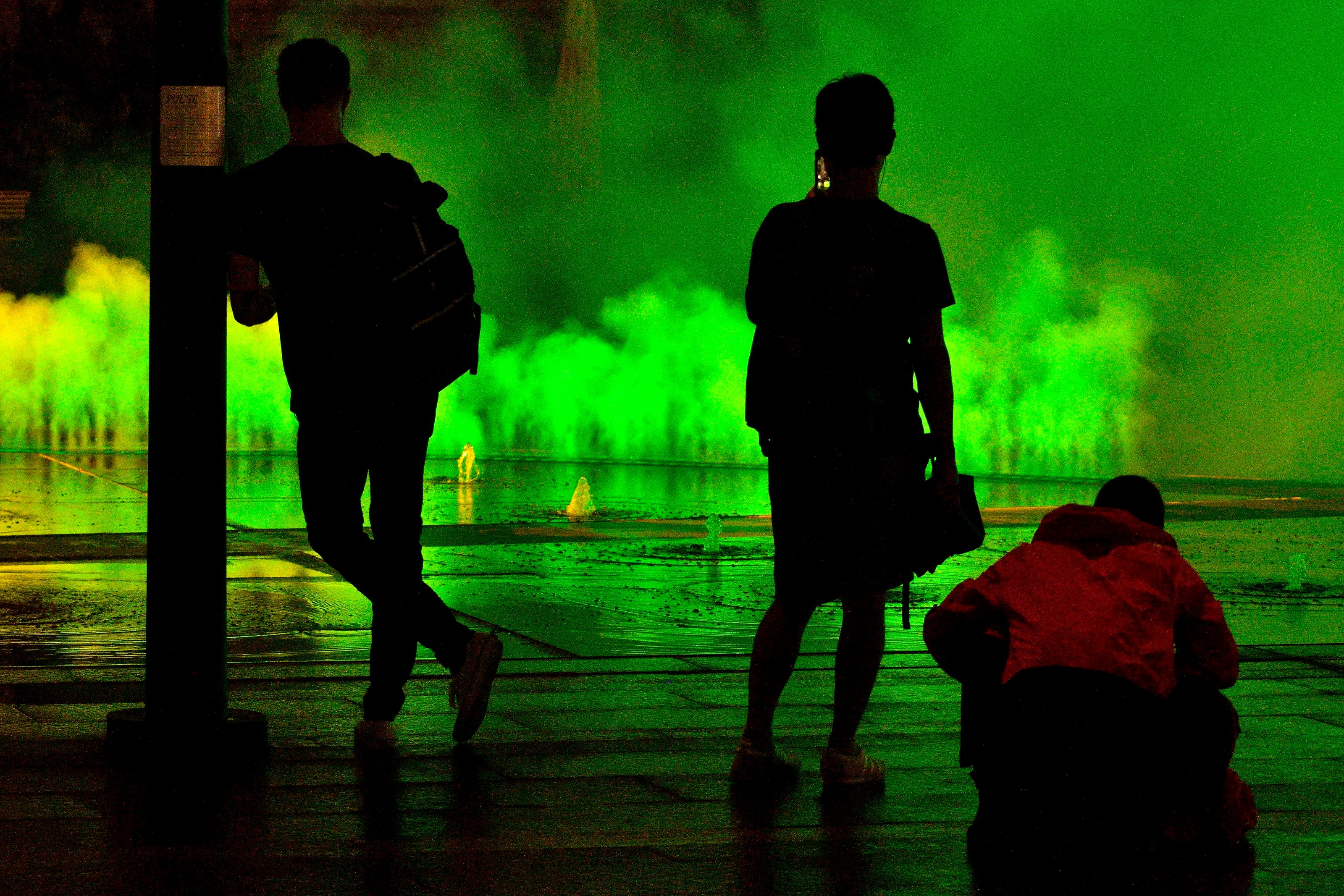 Passersby enjoy watch the green mist rise out of Pulse, the new installation at Dilwoerth Park. (Bastian Slabbers for WHYY)