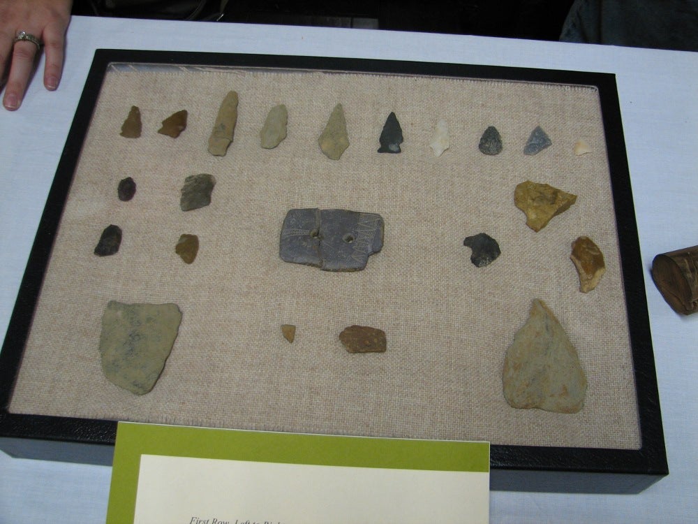 A display of arrowheads and an amulet found in I-95 archaeology
