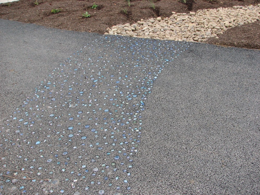 The blue glass stones embedded in the trail suggest water