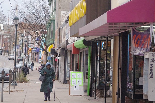 A shopper passes a cell phone store on Chelten Avenue in Germantown. (Jenny Swigoda/For NewsWorks)