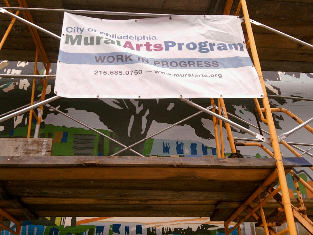 The Treaty Elm peaks out from behind the Mural Arts Program sign and scaffolding