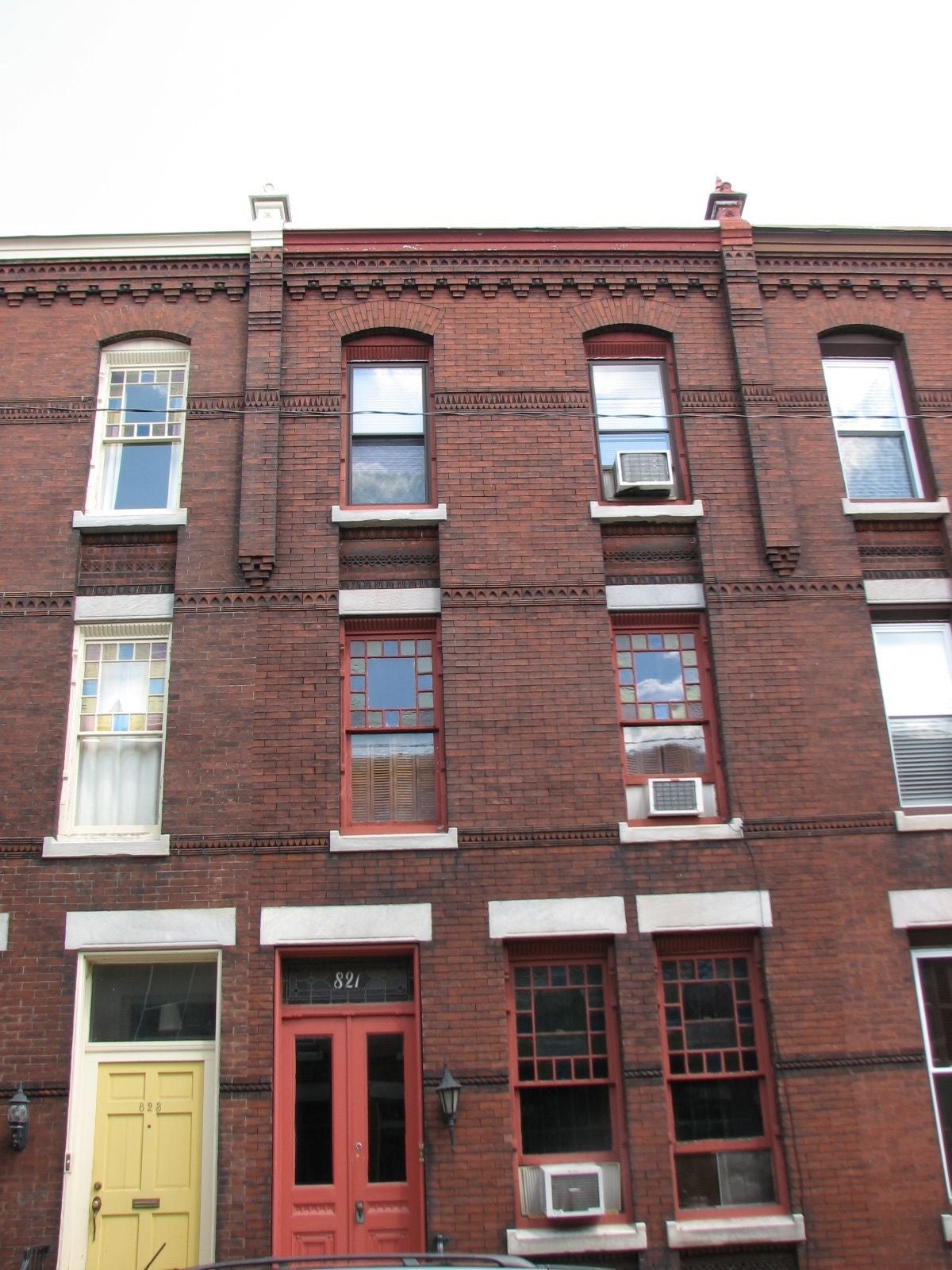 A corbelled roofline and colored glass panes around the windows unify the houses on the 800 block of North Woodstock.