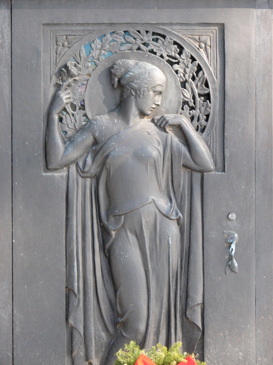 An Art Nouveau figure adorns the entrance of a mausoleum