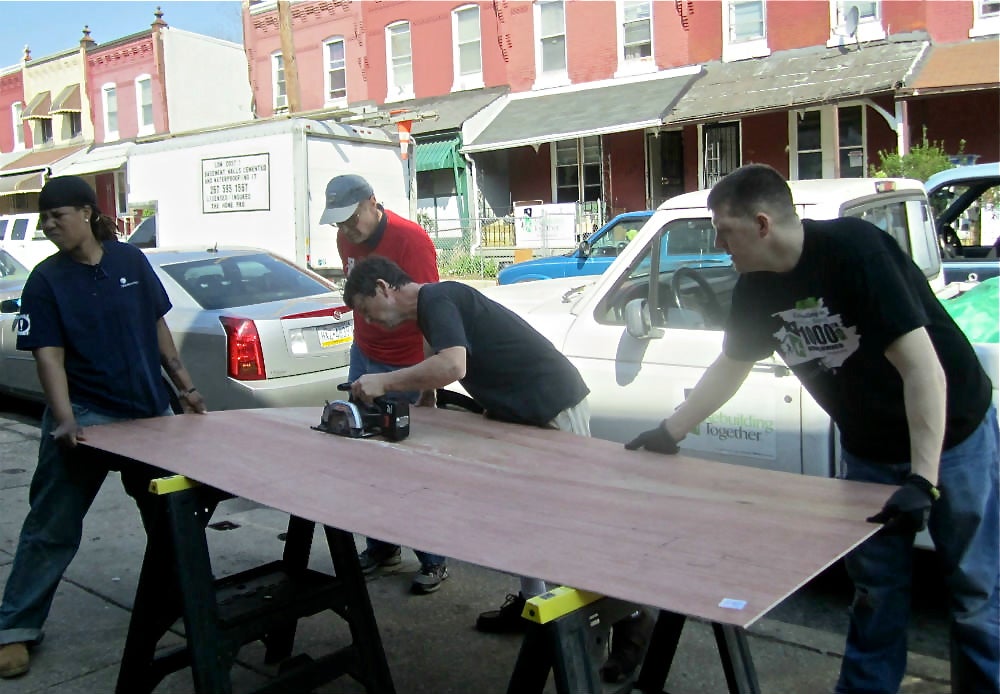 Volunteers brace plywood as it is cut for use in one of the Aspen Street homes. | Christine Fisher