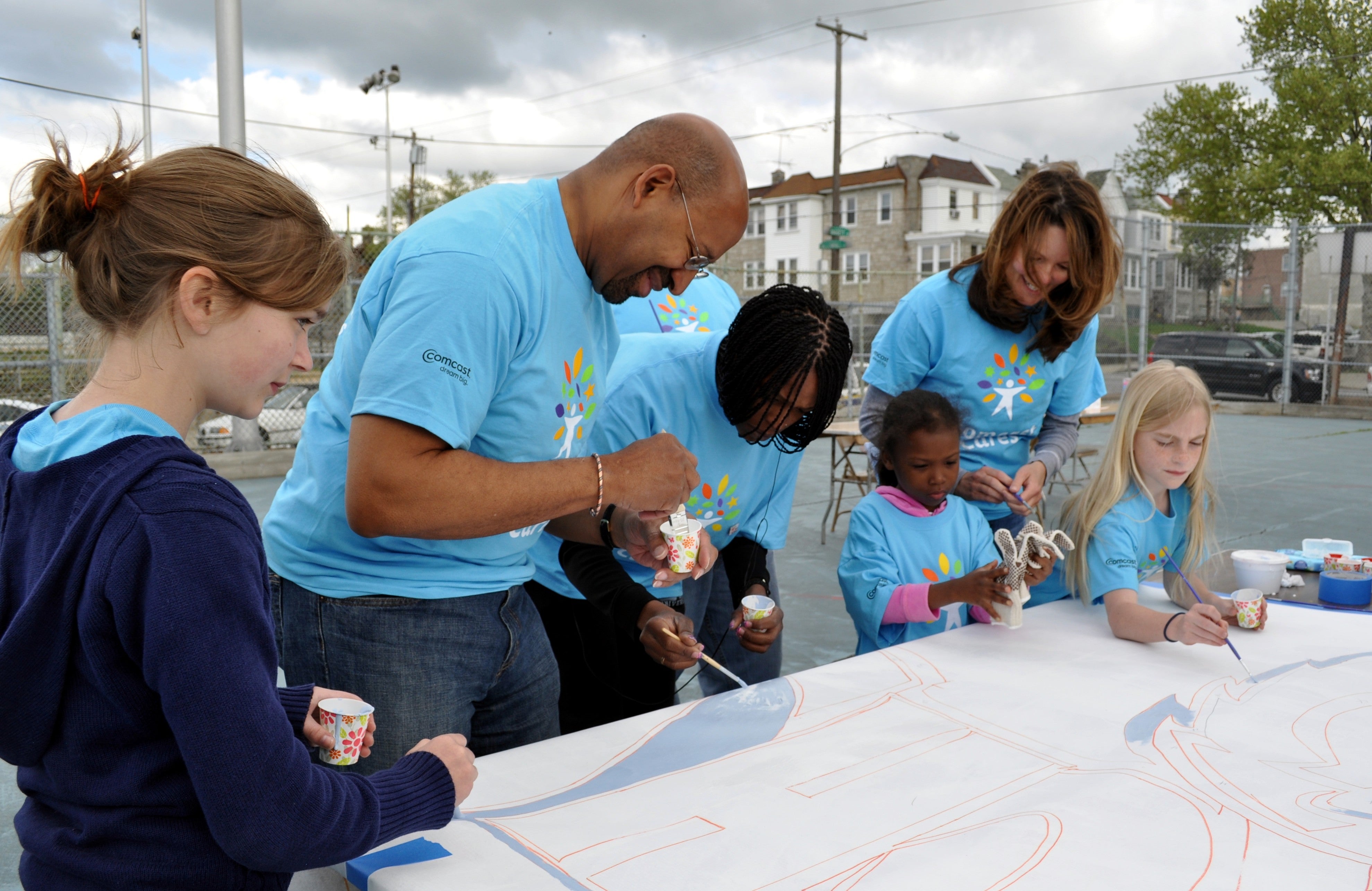 Mayor Michael Nutter (L) and Comcast's Amy Smith (R) pitch in to help a group of young Comcast Cares Day volunteers with a paint