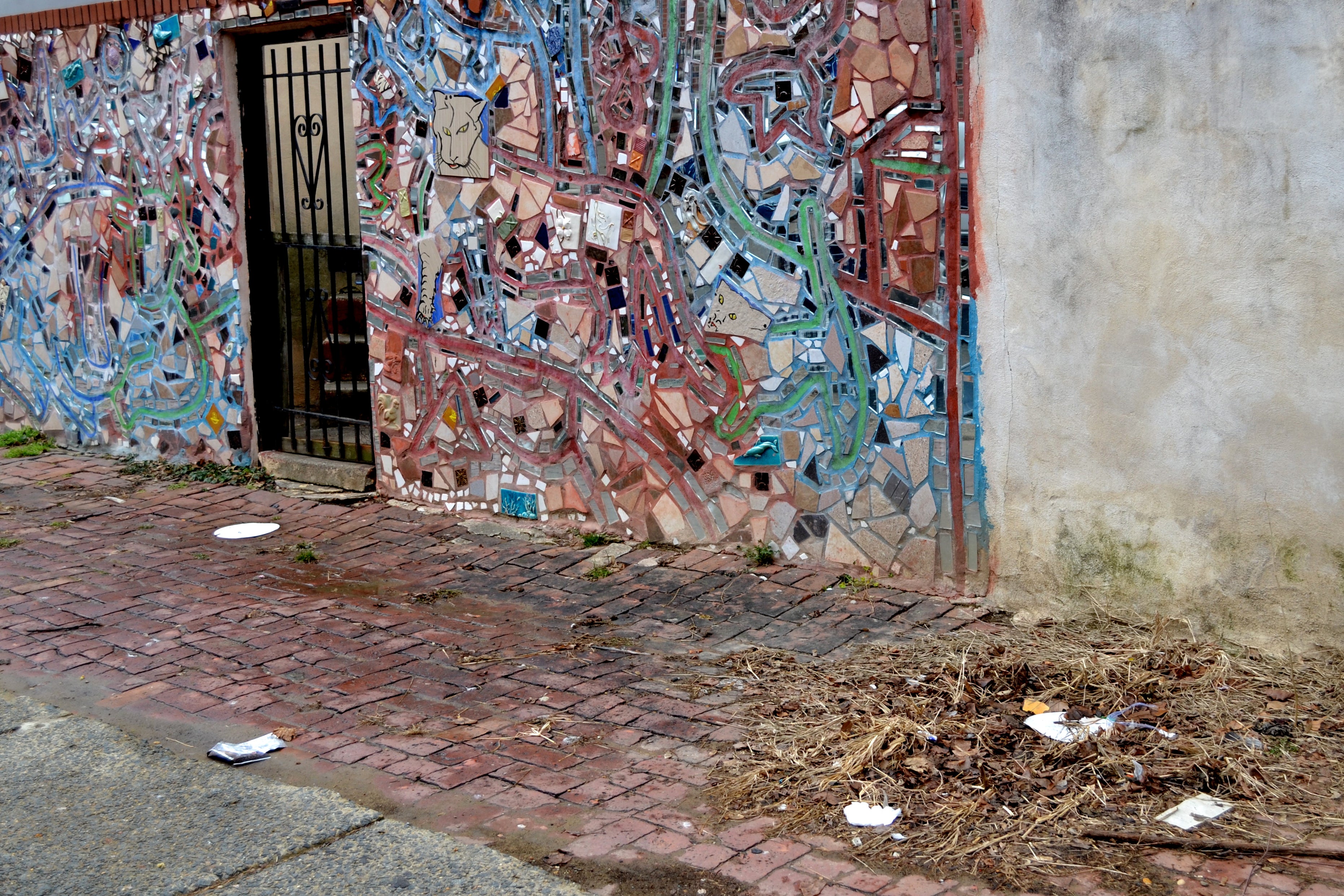 Trash litters the street in front of a South Philly mosaic