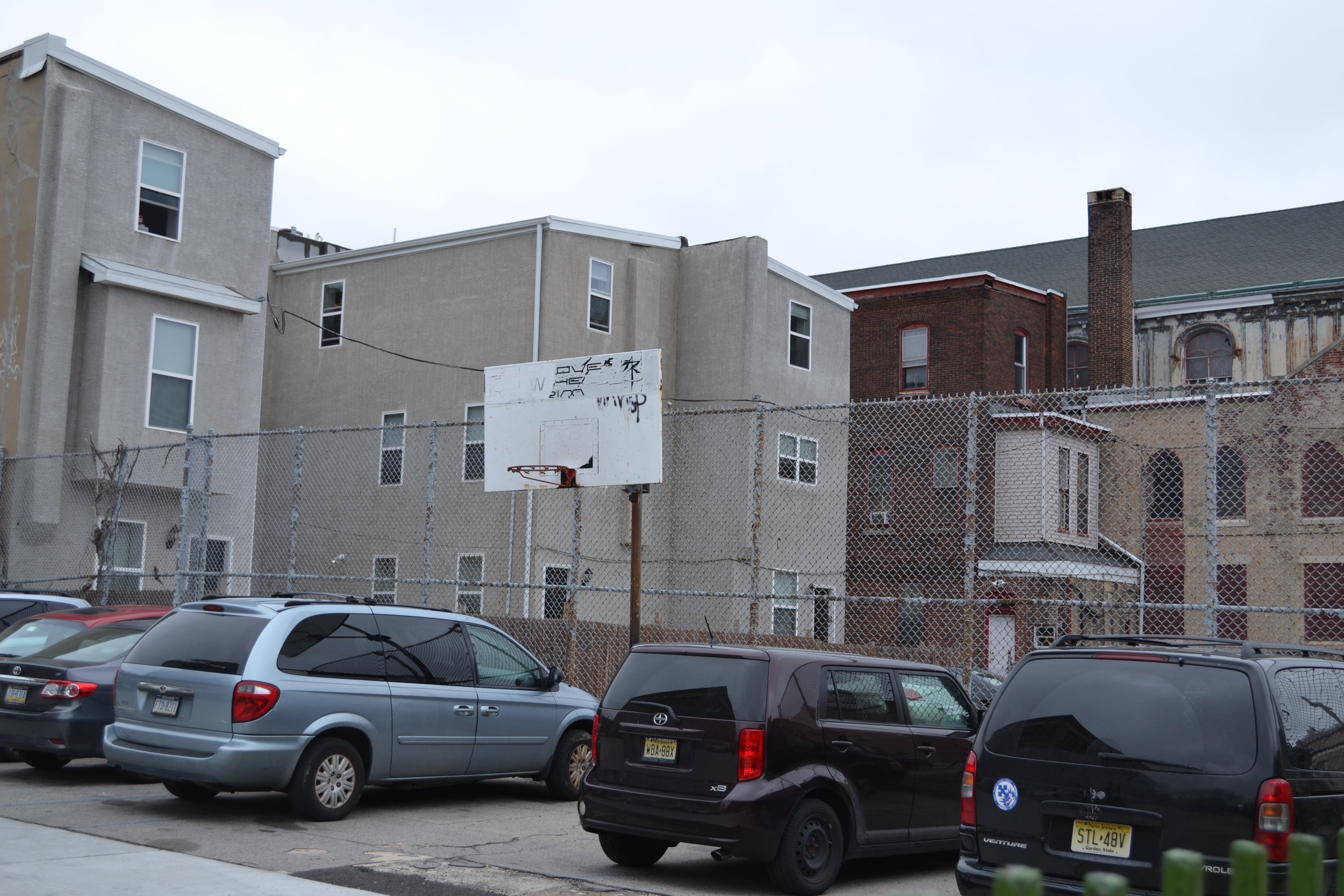 At the far end of the playground a tall fence behind the basketball hoop would help keep balls in the schoolyard