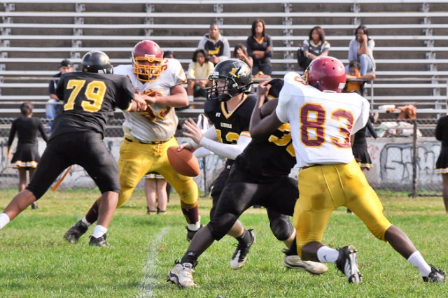 Lincoln's QB Joe McCausland (who also punts, places kick and plays defense) breaks into the open on a run while keeping his eyes open for potential receivers. He's aided in his escape from the