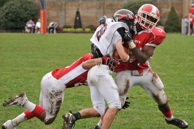 Falcons seniors wide receiver/defensive back Mark Allen (#20) and running back/ defensive back David William (#34) take down Raider wide receiver/defensive back Dom Vinciguerra at the end of the first