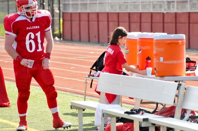 Stephen Rooney, a senior lineman awaits patiently for a refill as water girl, Alex Szydlik sets up cups filled with Gatorade or water.