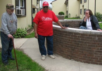 Dale Heverline (left), Jesse Lofton (center) and Carmen Rivas (right) discuss and admire the gardens Heverline and Lofton built outside their apartment building in the Holmecrest Homes.