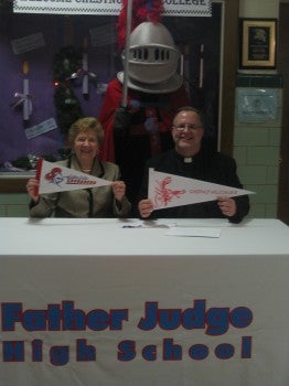 Chestnut Hill College President Sr. Carol Jean Vale, SSJ, and Father Judge High School President Fr. Joe Campellone celebrate their signed agreement with the help of the Father Judge Crusader.