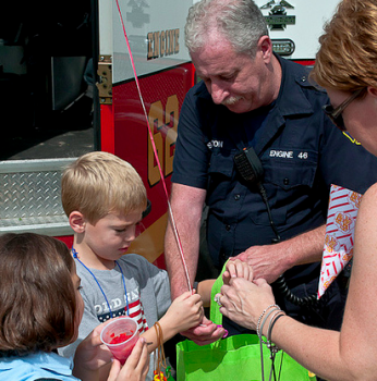 Firefighter Stanston helps a young boy with his items from the days event. Photo by George Mai. Firefighter Stanston helps a young boy with his items from the days event. Photo by George Mai.